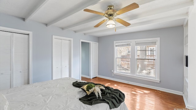 bedroom featuring beam ceiling, two closets, and ceiling fan