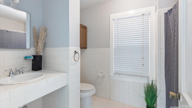 bathroom with tile walls, sink, toilet, and tile patterned flooring