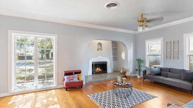 living room with crown molding, wood-type flooring, and a wealth of natural light