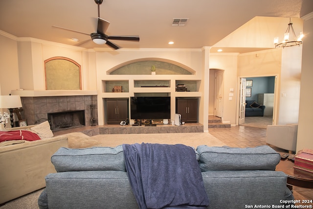 tiled living room with crown molding, a fireplace, and ceiling fan with notable chandelier