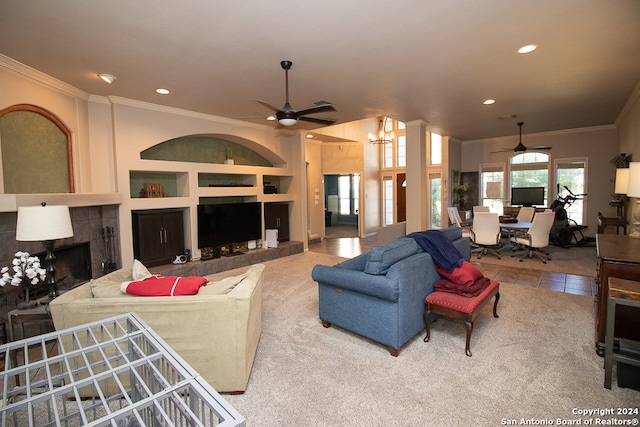 tiled living room featuring a tile fireplace, built in shelves, ceiling fan with notable chandelier, and ornamental molding