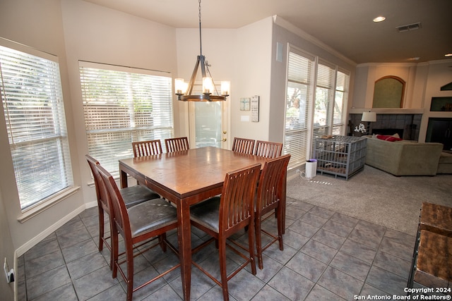 dining room with carpet, a notable chandelier, a wealth of natural light, and a tiled fireplace