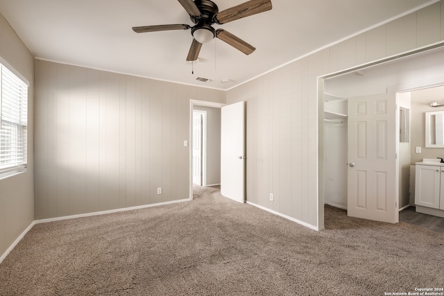 unfurnished bedroom featuring carpet, a walk in closet, a closet, and ceiling fan