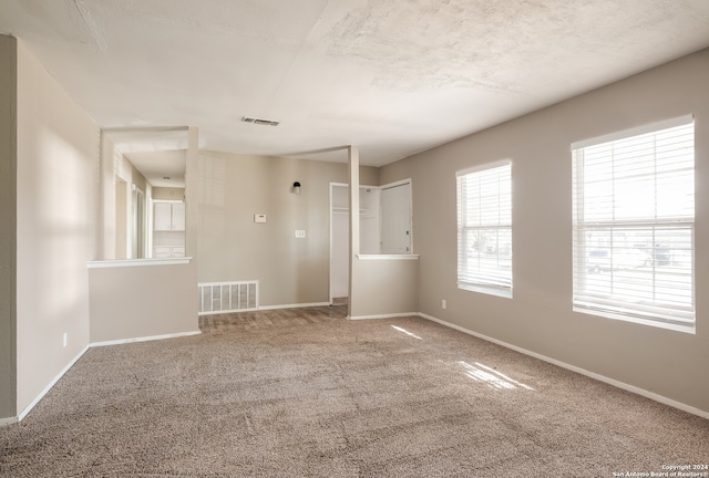 carpeted spare room with a textured ceiling