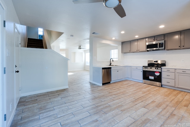 kitchen with gray cabinets, light hardwood / wood-style flooring, stainless steel appliances, and sink