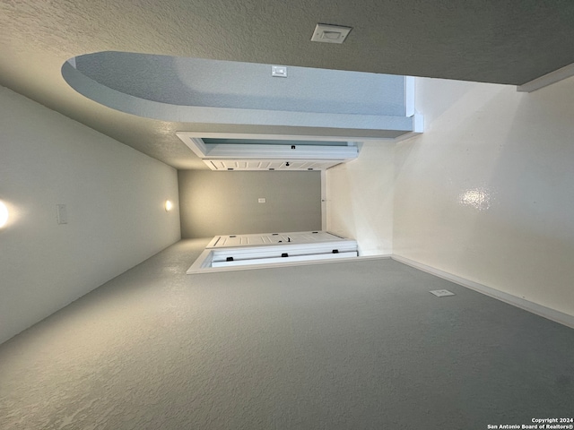 hallway featuring a textured ceiling, a tray ceiling, and carpet flooring