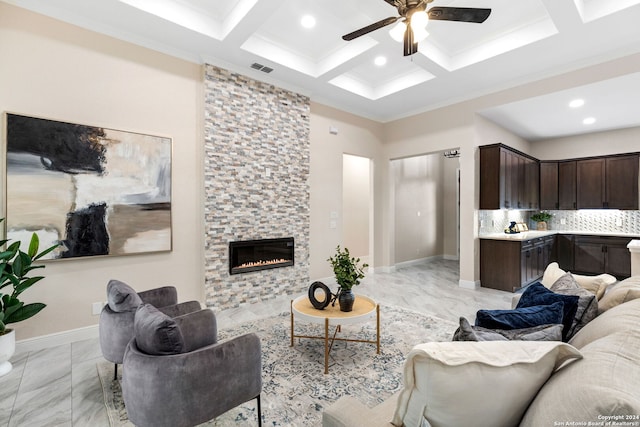 living room featuring coffered ceiling, a stone fireplace, beam ceiling, ornamental molding, and ceiling fan