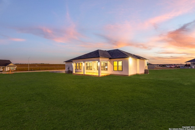 back house at dusk with a yard and a patio area