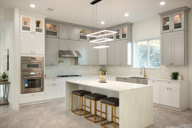 kitchen with a center island, sink, stainless steel double oven, gas cooktop, and gray cabinets