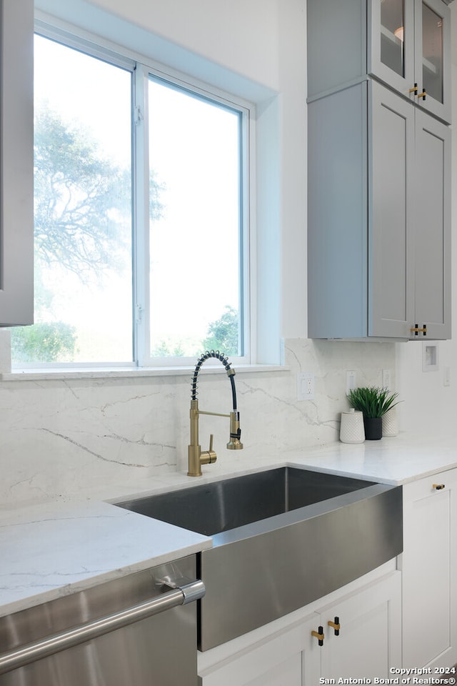 kitchen featuring dishwasher, light stone counters, sink, and tasteful backsplash