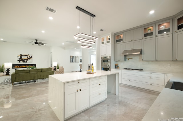 kitchen with gray cabinetry, ceiling fan, stainless steel appliances, pendant lighting, and a kitchen island