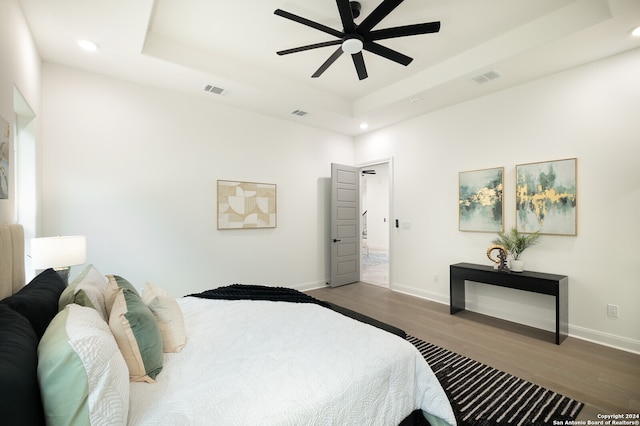 bedroom with a tray ceiling, ceiling fan, and dark hardwood / wood-style floors