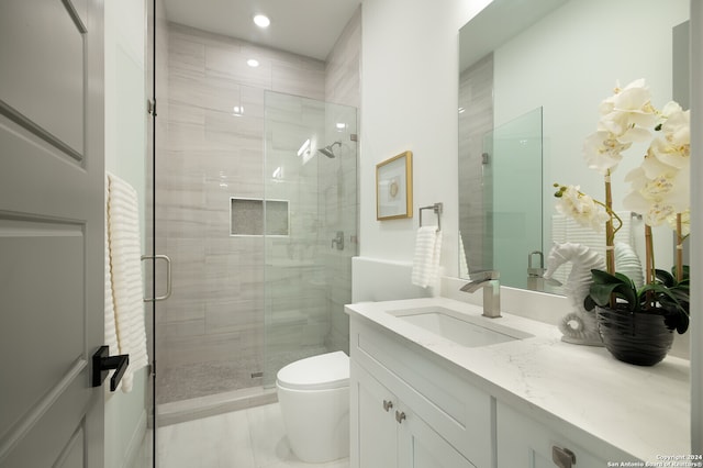 bathroom featuring tile patterned flooring, vanity, toilet, and a shower with door