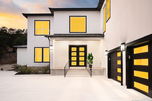 back house at dusk featuring a garage