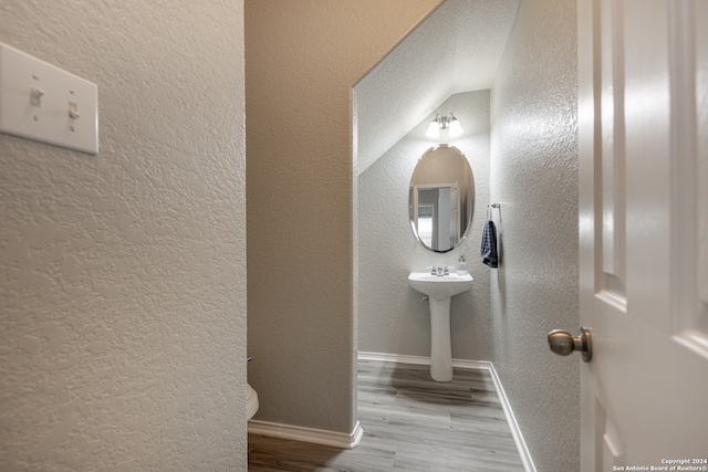 bathroom with vaulted ceiling, hardwood / wood-style flooring, and sink