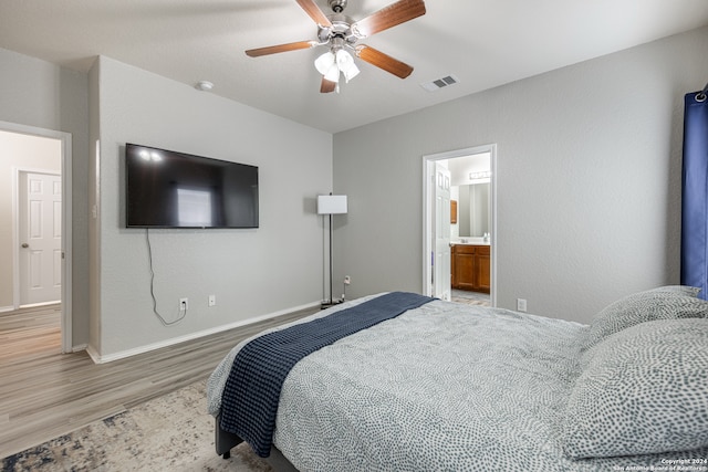 bedroom with ceiling fan, ensuite bathroom, and light wood-type flooring