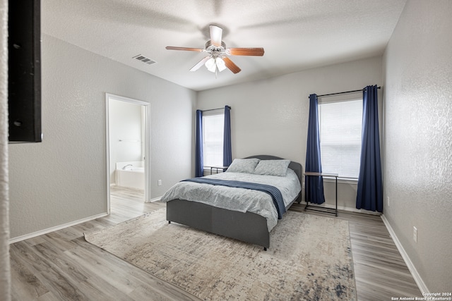 bedroom with connected bathroom, a textured ceiling, hardwood / wood-style flooring, and ceiling fan