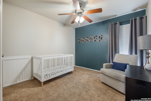 bedroom with a nursery area, light colored carpet, and ceiling fan