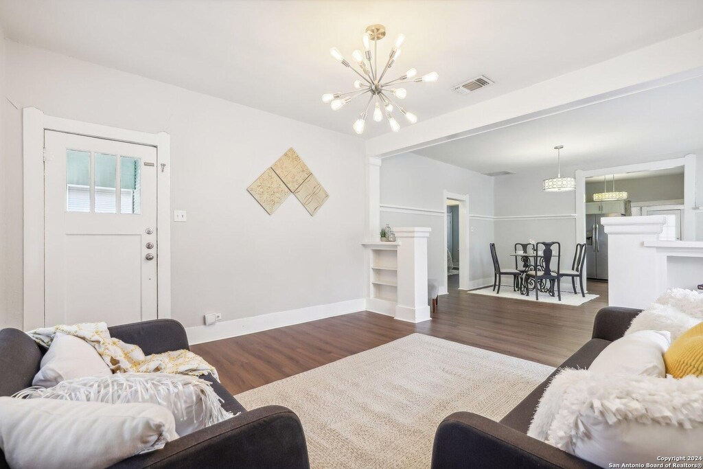 1112 W Huisache Ave, San Antonio, TX 78201 - living room featuring baseboards, a notable chandelier, wood finished floors, and visible vents