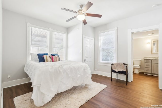 bedroom featuring ensuite bath, dark wood-type flooring, and ceiling fan