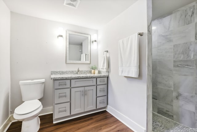 bathroom with vanity, tiled shower, wood-type flooring, and toilet