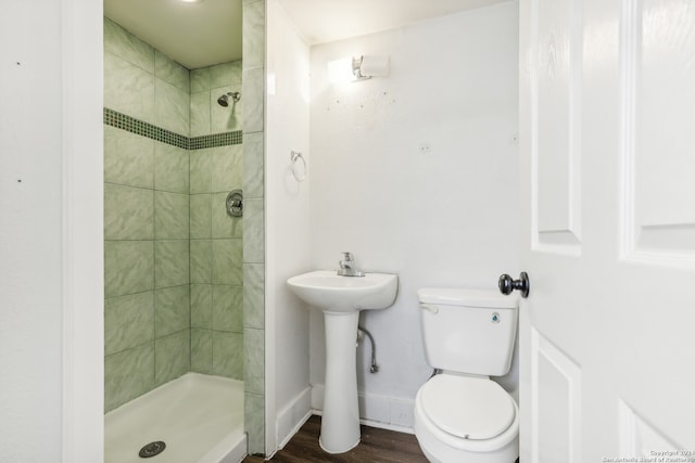 bathroom featuring sink, a tile shower, hardwood / wood-style flooring, and toilet