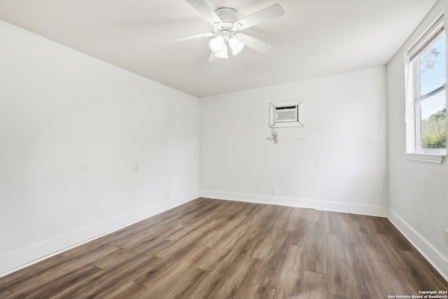 unfurnished room with ceiling fan, an AC wall unit, and hardwood / wood-style floors