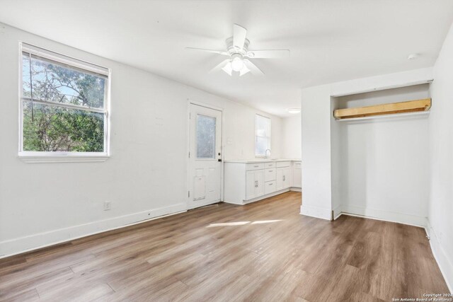 1112 W Huisache Ave, San Antonio, TX 78201 - unfurnished bedroom with a sink, baseboards, multiple windows, and light wood-type flooring