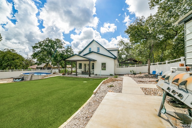 back of property featuring a yard, a patio area, and a fenced in pool