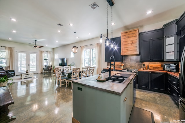 kitchen with backsplash, plenty of natural light, a center island with sink, and hanging light fixtures