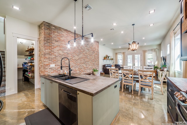 kitchen featuring appliances with stainless steel finishes, an island with sink, pendant lighting, brick wall, and an inviting chandelier