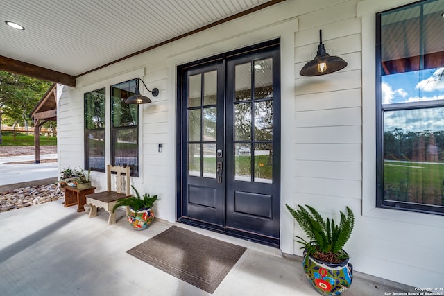 view of exterior entry featuring french doors and covered porch