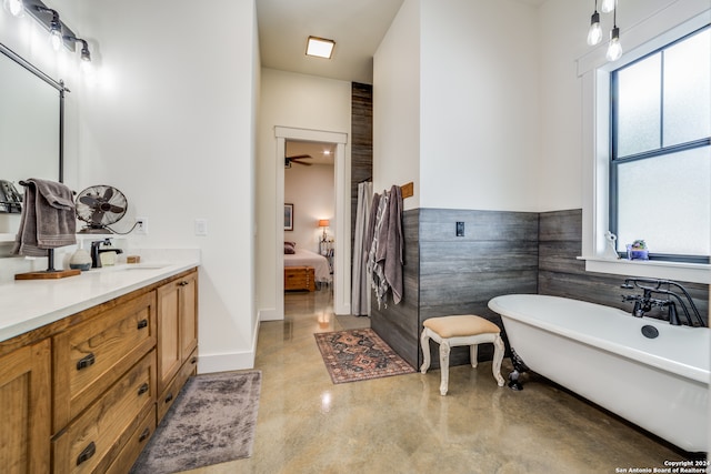 bathroom featuring a tub, ceiling fan, concrete floors, tile walls, and vanity