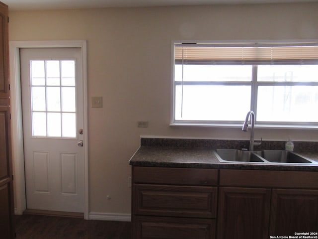 kitchen with dark brown cabinetry, sink, and dark wood-type flooring