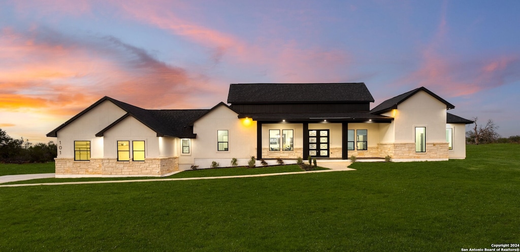 back house at dusk with a lawn