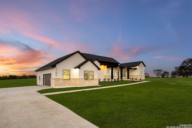 view of front of home with a garage and a lawn