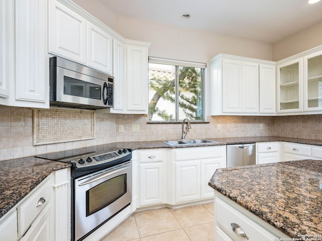 kitchen featuring decorative backsplash, white cabinetry, dark stone countertops, sink, and stainless steel appliances