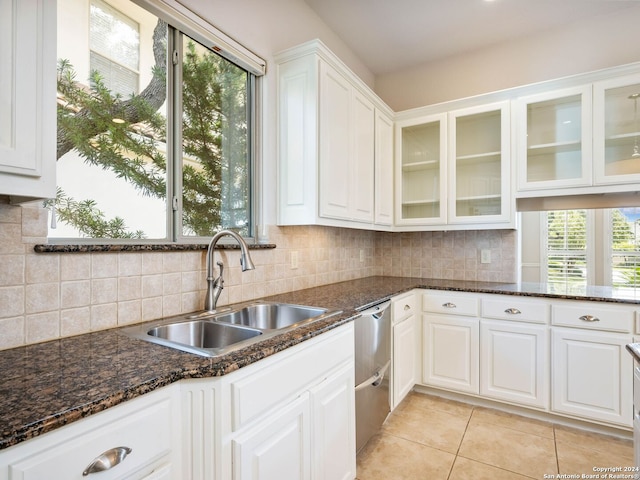 kitchen featuring decorative backsplash, white cabinetry, stainless steel dishwasher, dark stone counters, and sink