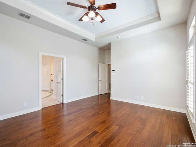 spare room featuring ceiling fan, wood-type flooring, a tray ceiling, and ornamental molding