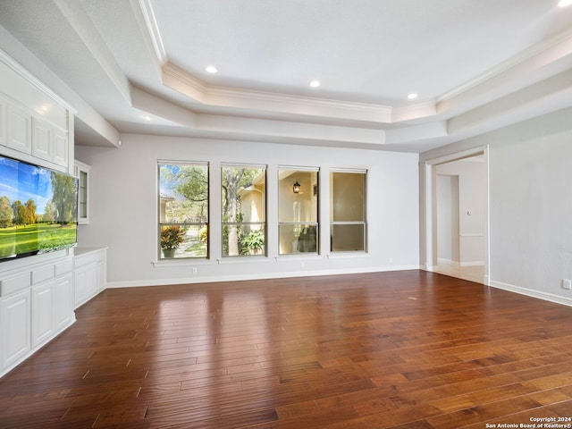 unfurnished living room with a raised ceiling, ornamental molding, and dark hardwood / wood-style floors