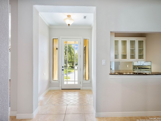 doorway with ornamental molding and light tile patterned flooring