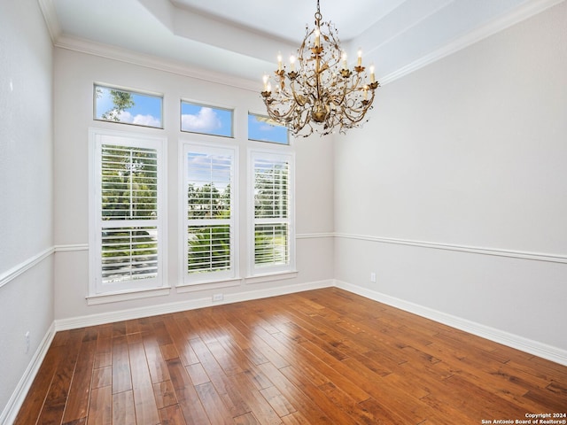 unfurnished room with ornamental molding, hardwood / wood-style floors, and a notable chandelier