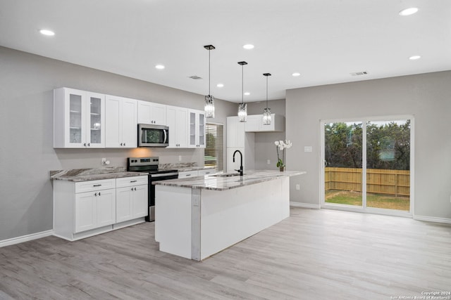 kitchen featuring appliances with stainless steel finishes, a center island with sink, light stone counters, and sink