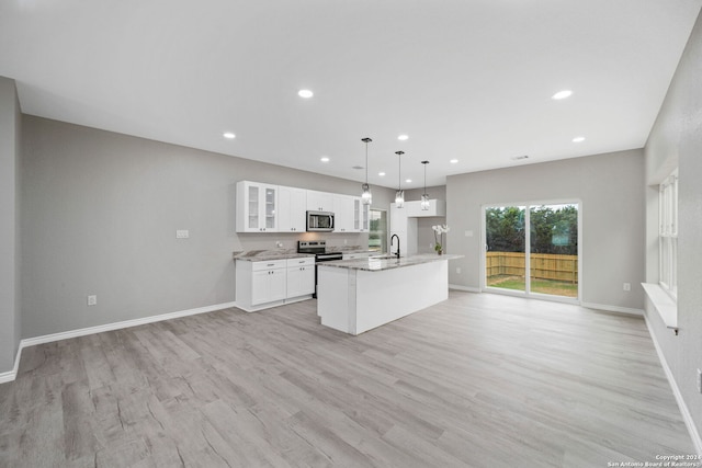 kitchen with an island with sink, hanging light fixtures, white cabinetry, appliances with stainless steel finishes, and light hardwood / wood-style floors