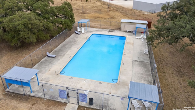 view of swimming pool featuring a storage unit and a patio area