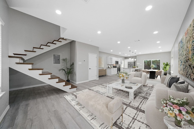 unfurnished living room with an inviting chandelier and light wood-type flooring