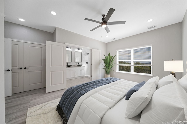 bedroom featuring a closet, light hardwood / wood-style floors, ensuite bath, and ceiling fan