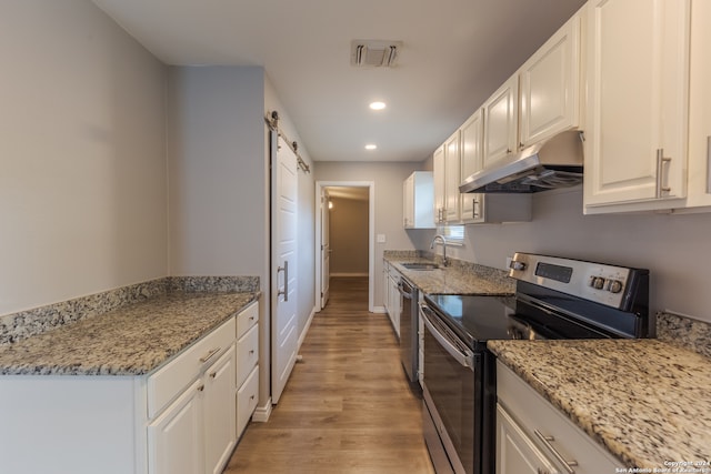 kitchen featuring sink, a barn door, white cabinets, appliances with stainless steel finishes, and light hardwood / wood-style floors