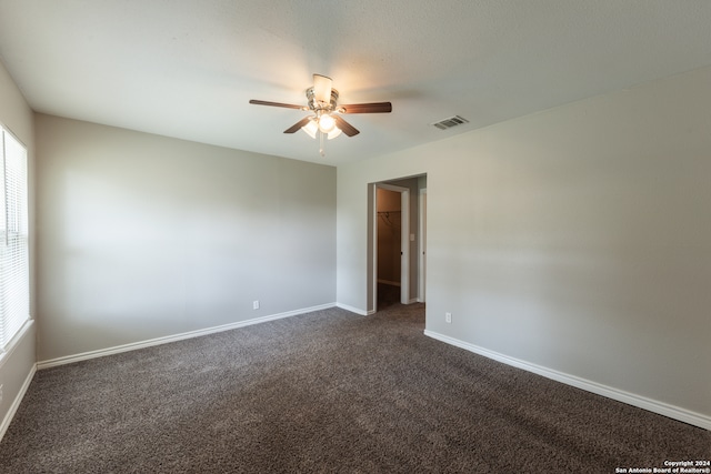 unfurnished room featuring dark colored carpet and ceiling fan