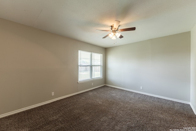 spare room with ceiling fan, a textured ceiling, and dark carpet